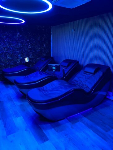 A row of three black HydroMassage beds in a dimly lit room with blue ambient lighting.