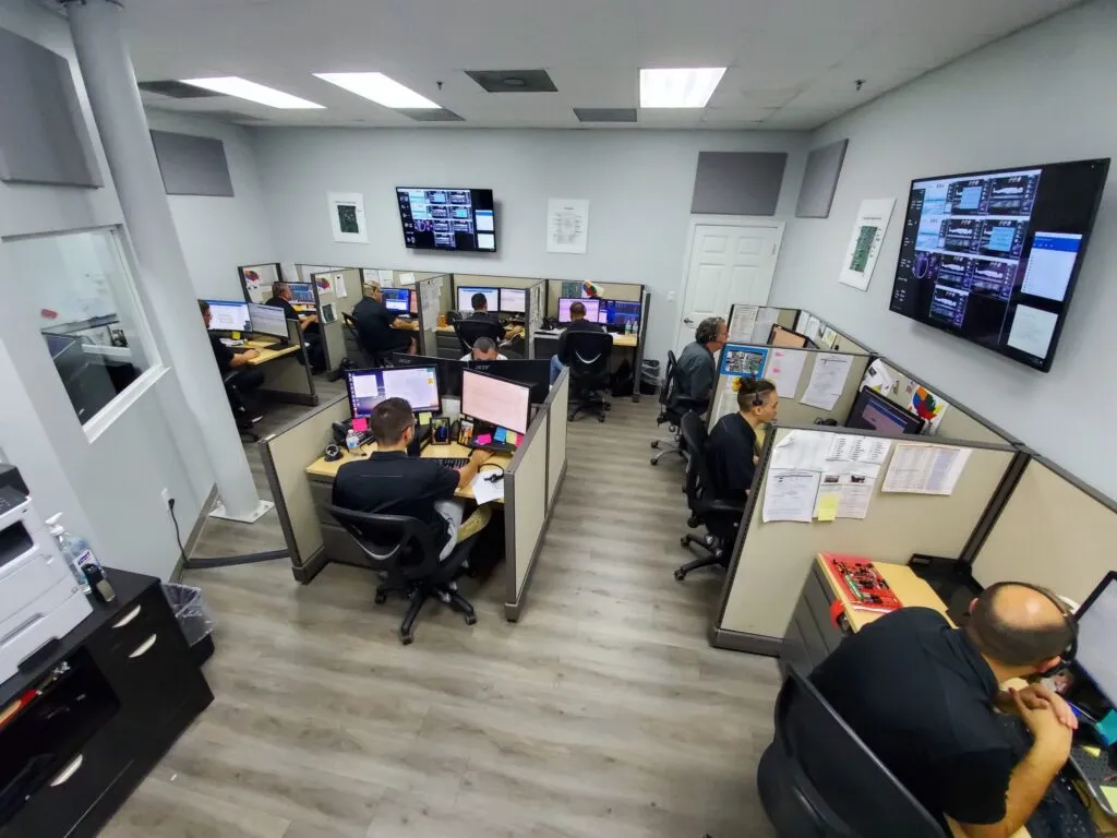 WellnessSpace Brands tech support office with multiple employees working in cubicles, each equipped with dual monitors and headsets