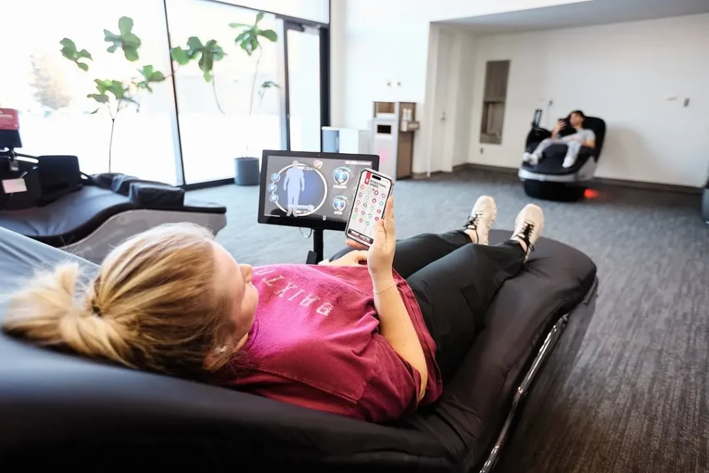 Woman lying on a HydroMassage lounge using a smartphone