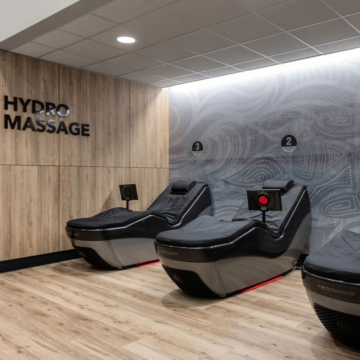 Three black HydroMassage beds in a room with wood panel walls and a sign reading "HYDRO MASSAGE."