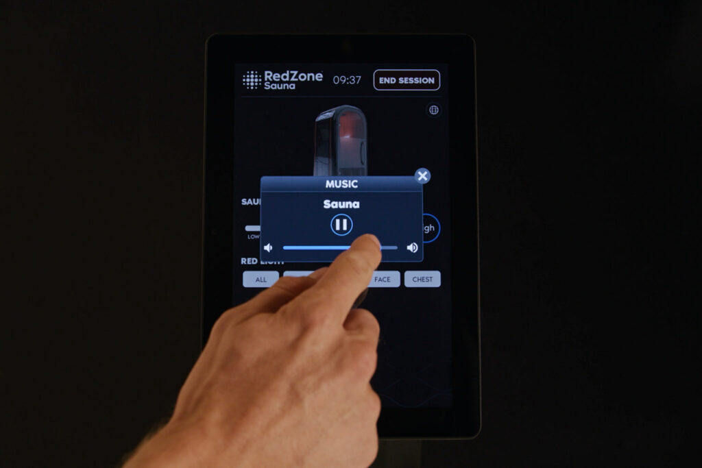 Hand adjusting music volume on the RedZone Sauna touchscreen