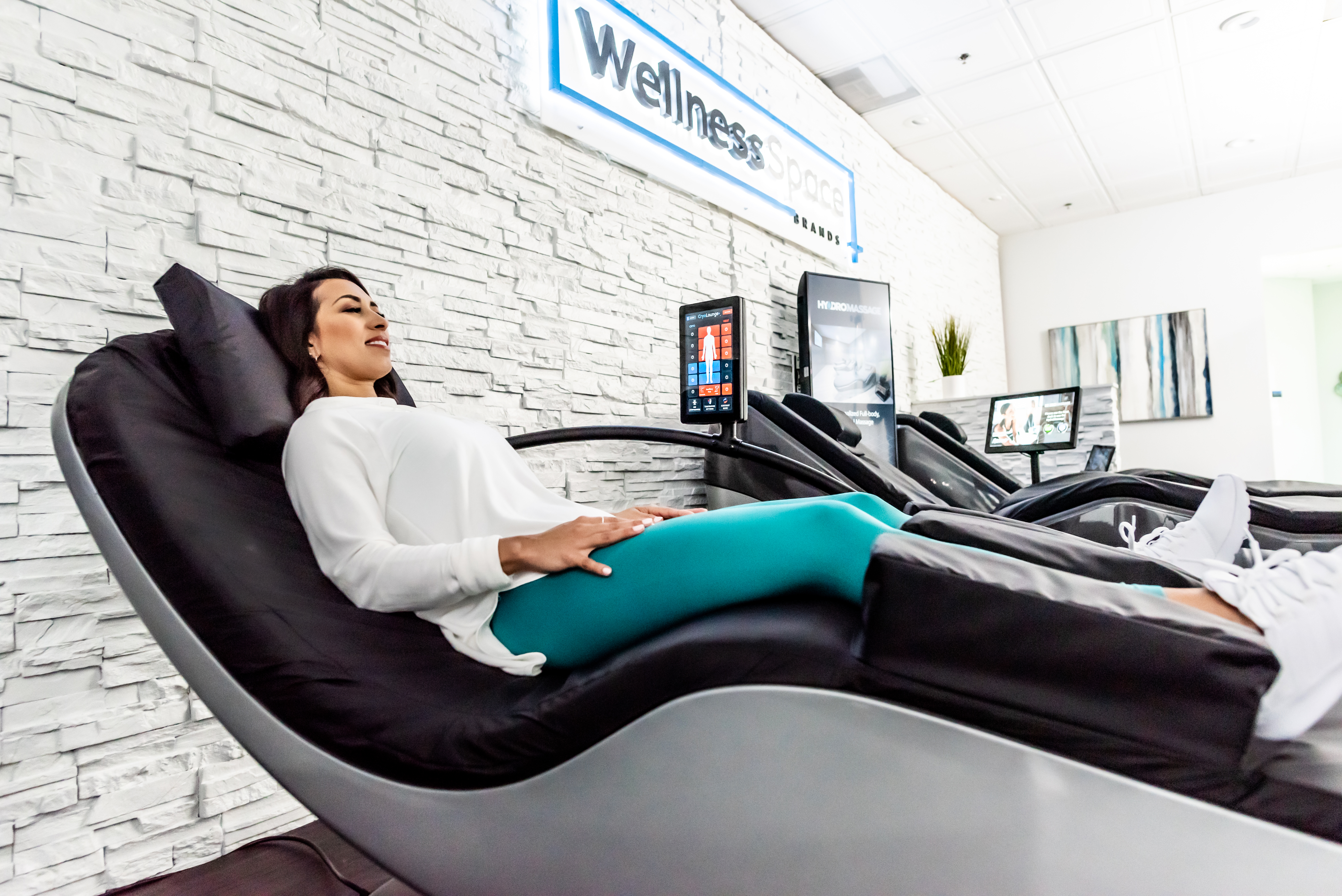 Member using a self-service wellness recovery chair inside a WellnessSpace Brands recovery area.