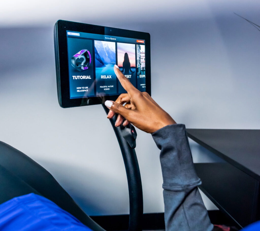 Close-up of a touchscreen interface on a WellnessSpace Brands wellness recovery system, showing guided session options.