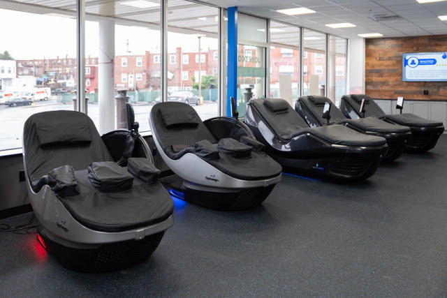 Multiple self-service wellness recovery loungers arranged in a commercial gym recovery space.